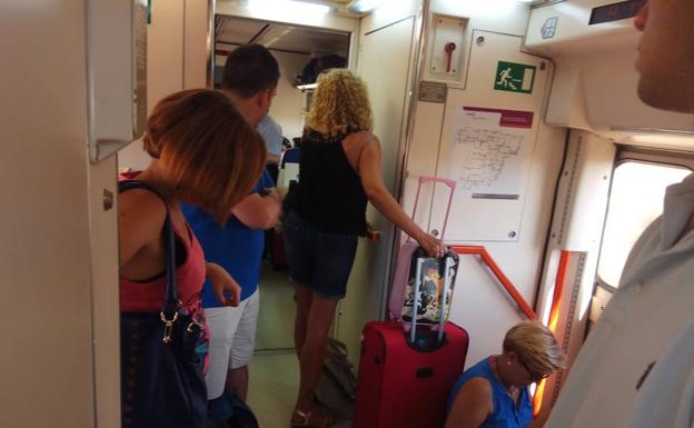 Viajeros de pie en el tren que recogió el jueves a los que se bajaron de otro que paró en Humanes (Madrid) al salir ardiendo un vagón. 