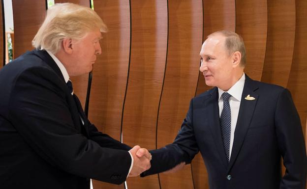 Donald Trump y Vladimir Putin se estrechan la mano.