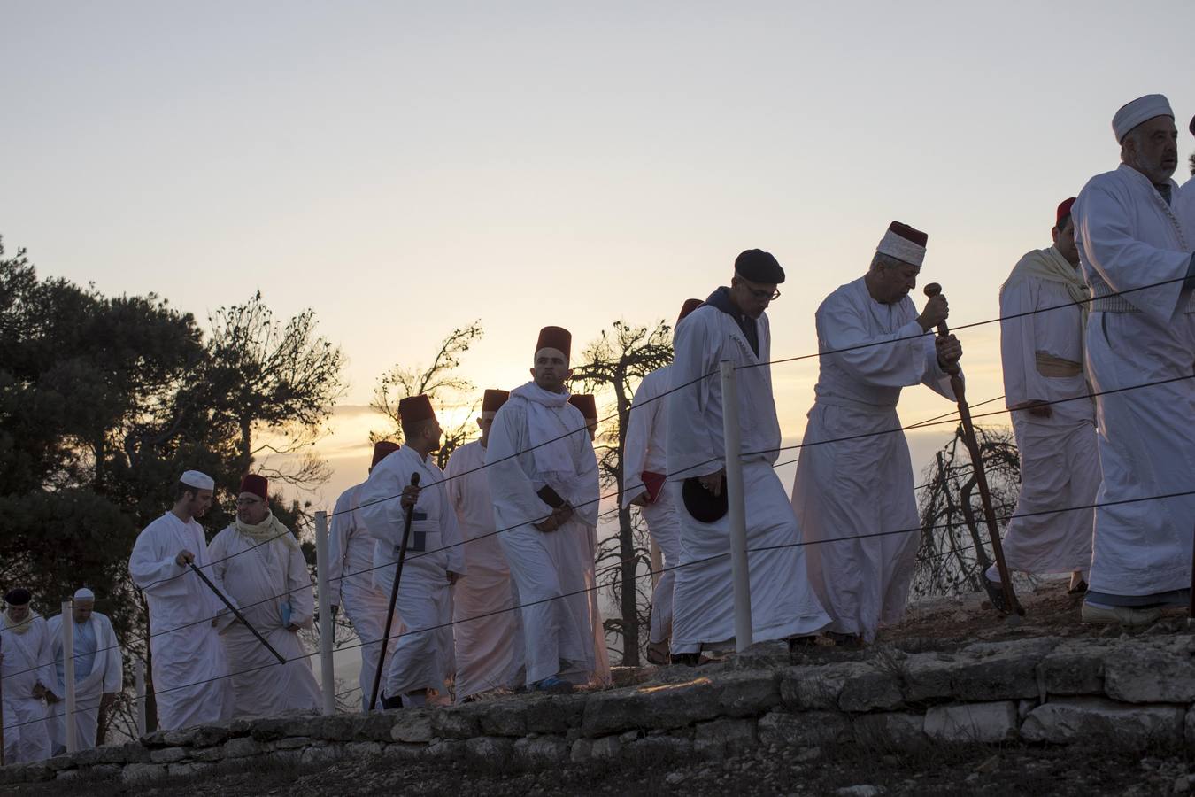 Miembros de la comunidad samaritana caminan hacia la cima del Monte Guerizín al amanecer en Nablus (Palestina), con motivo de la celebración del Sukot o fiesta de los tabernáculos.