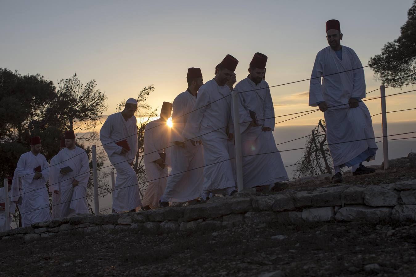 Miembros de la comunidad samaritana caminan hacia la cima del Monte Guerizín al amanecer en Nablus (Palestina), con motivo de la celebración del Sukot o fiesta de los tabernáculos.