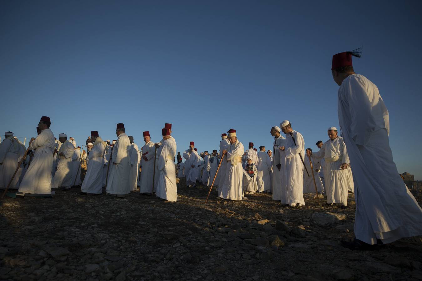 Miembros de la comunidad samaritana caminan hacia la cima del Monte Guerizín al amanecer en Nablus (Palestina), con motivo de la celebración del Sukot o fiesta de los tabernáculos.