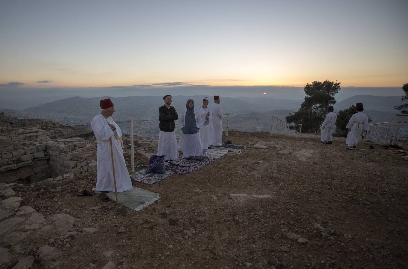 Miembros de la comunidad samaritana caminan hacia la cima del Monte Guerizín al amanecer en Nablus (Palestina), con motivo de la celebración del Sukot o fiesta de los tabernáculos.