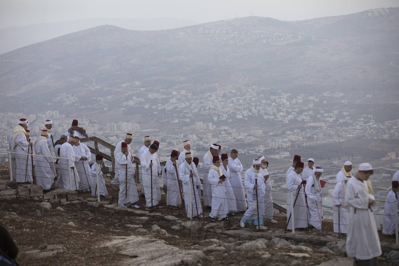 Miembros de la comunidad samaritana caminan hacia la cima del Monte Guerizín al amanecer en Nablus (Palestina), con motivo de la celebración del Sukot o fiesta de los tabernáculos.