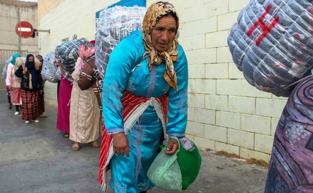 Varias mujeres cargan con grandes fardos en la frontera afroespañola. 