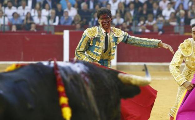 Cayetano Rivera, con el rostro ensangrentado, tras sufrir una cornada en la pierna, junto a Ponce.