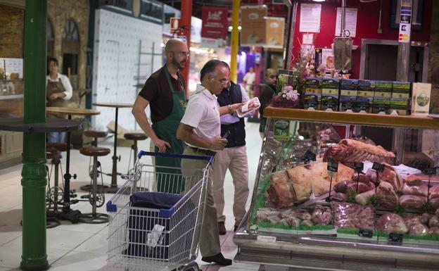 Un empleado de Amazon Prime Now hace compra productos frescos para un cliente en el Mercado de la Paz de Madrid.