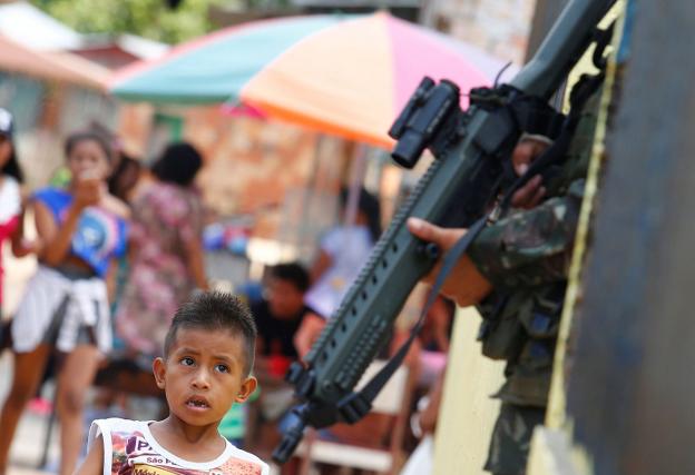 Un niño indígena observa el arma de un soldado brasileño desplegado en las maniobras militares en Tabatinga. :: reuters