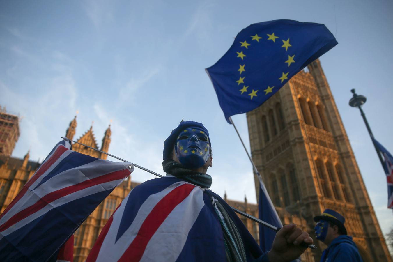 Los manifestantes pro-Unión Europea, (UE) y anti-Brexit usan máscaras con la bandera de la UE, ya que sostienen una bandera de la Unión fuera del Parlamento en el centro de Londres el 18 de diciembre de 2017. / AFP PHOTO / 