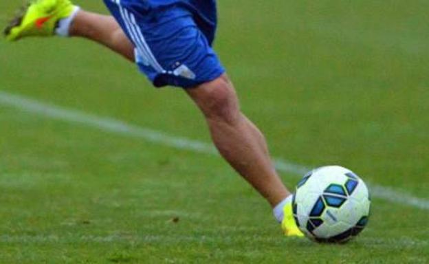 Un futbolista se dispone a golpear un balón.