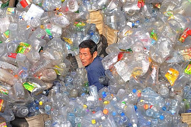 Un trabajador de una planta de tratamiento de residuos plásticos de Shenyang, al noreste de China, trata de abrirse paso entre un océano de envases.