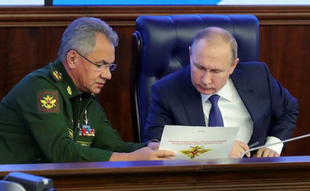 Putin (d) habla con Sergei Shoigu.