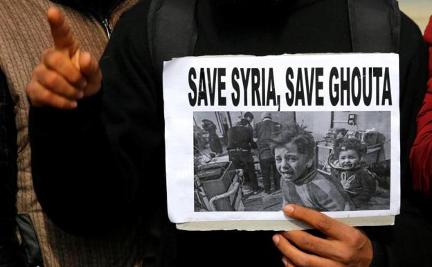 Un miembro del Foro Global de Investigación del Islam sostiene una pancarta en la que aparecen unos niños sirios en los bombardeos.