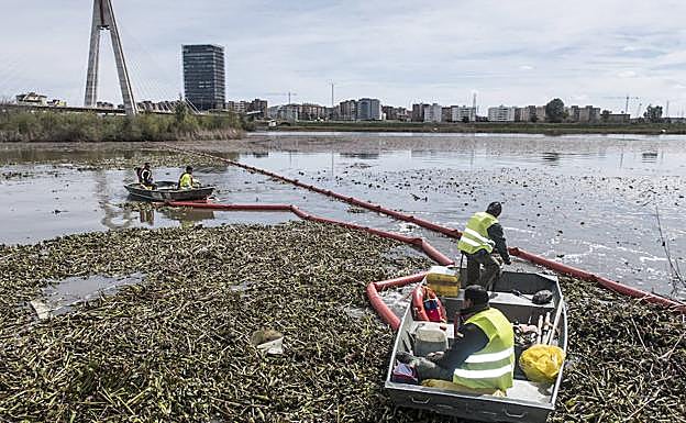 Cuatro operarios en dos barcas desplazan las barreras flotantes junto al Puente Real. :: Pakopí
