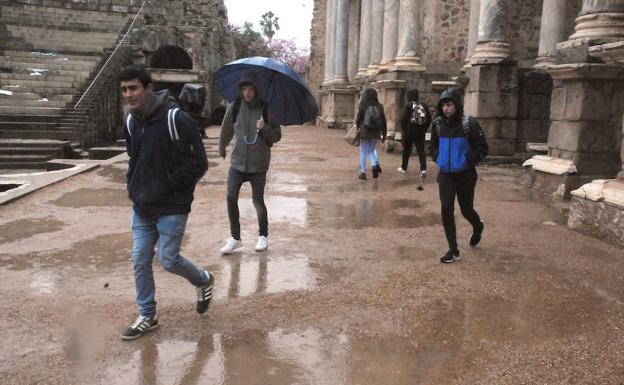 Jóvenes se protegen de la lluvia en el Teatro Romano de Mérida::