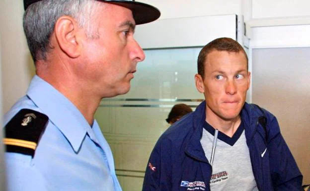 Lance Armstrong, junto a un gendarme francés antes de tomar un vuelo durante el Tour de 2001. 