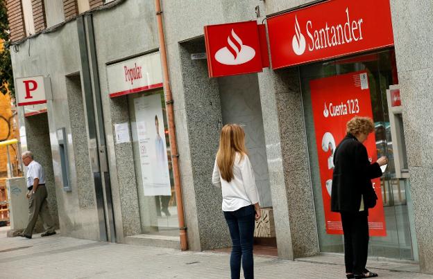 Dos clientas, en un cajero del Santander junto a una oficina del Popular. :: ALBERT GEA / reuters