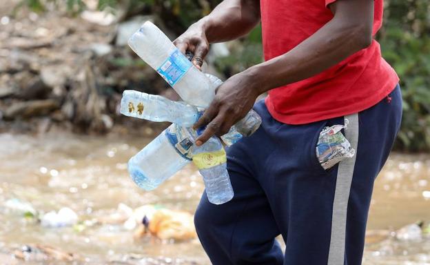 Un voluntario recoge botellas de plástico.