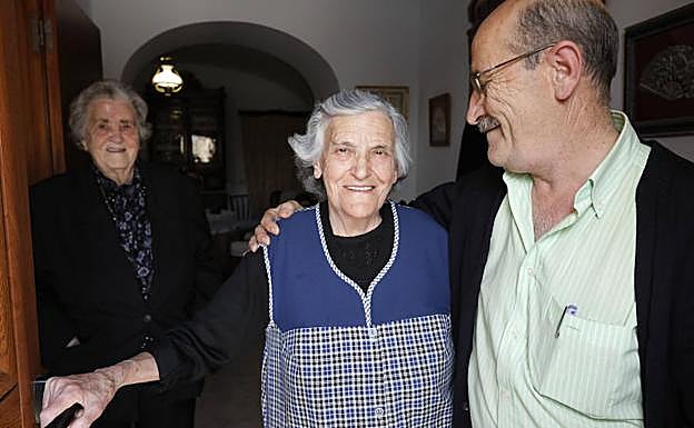 Imagen principal - Alfonso Barroso, alcalde de Torremocha, felicita a Claudia, con la tía Eugenia al fondo. | Foto de familia, con los padres de la ministra, ella y su hermano Martín, de pequeños. | Las vecinas con Claudia, que habla con su nieta Isabel por teléfono. 