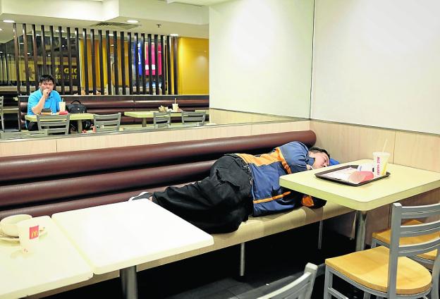 Un hombre pasa la noche en el McDonald's del distrito Sham Shui Po, en Hong Kong. :: reuters