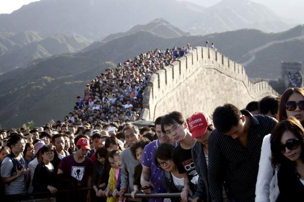 1.400 millones. La política del hijo único ha hundido las tasas de natalidad. A la derecha, miles de chinos abarrotan la Gran Muralla. 