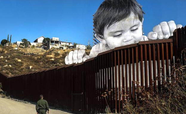 Un gente estadounidense observa el mural de un niño levantado en la frontera con México.