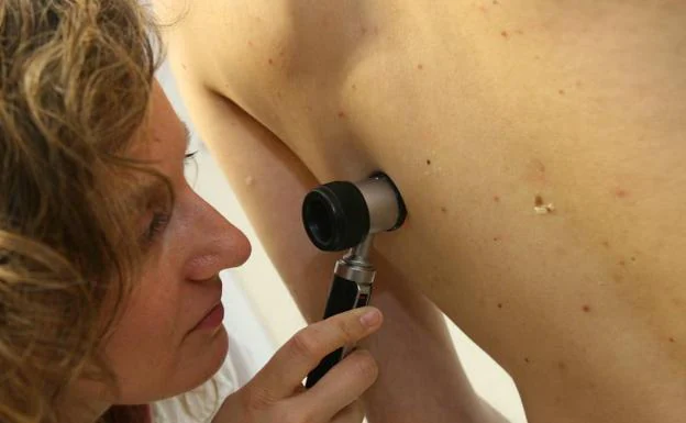 Una dermatóloga realiza una revisión en consulta. :: 