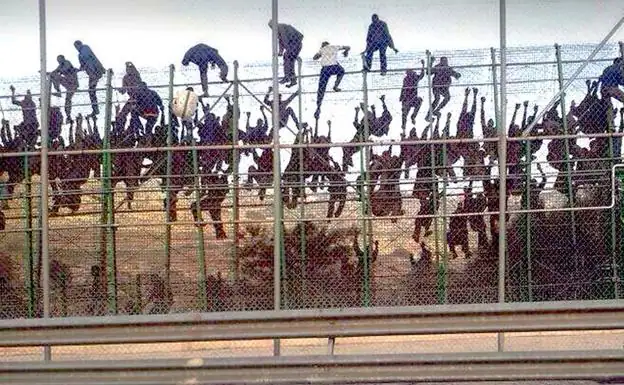 Decenas de inmigrantes escalando la valla de Melilla.