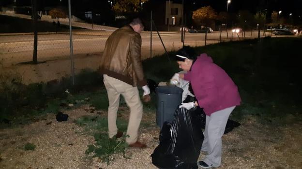 Dos ciudadanos recogen la basura durante la tarde noche del martes. :: hoy