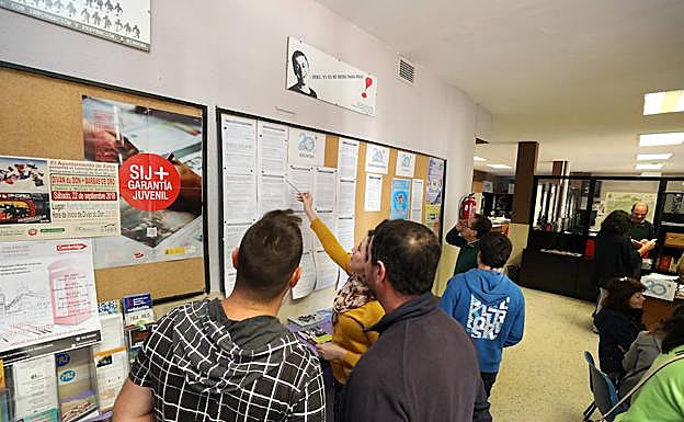 Varias personas miran la oferta en el centro de empleo de Zafra