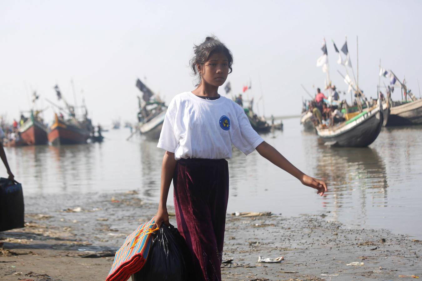 Policías birmanos escoltan al grupo de 106 rohinyás de vuelta a Sittwe en el estado de Rakáin (Birmania). El pasado 16 de noviembre, el barco en el que viajaban los 106 rohinyás encalló en la costa cerca de Rangún, con uno de sus ocupantes muerto, cuando trataba de llegar a Malasia. 