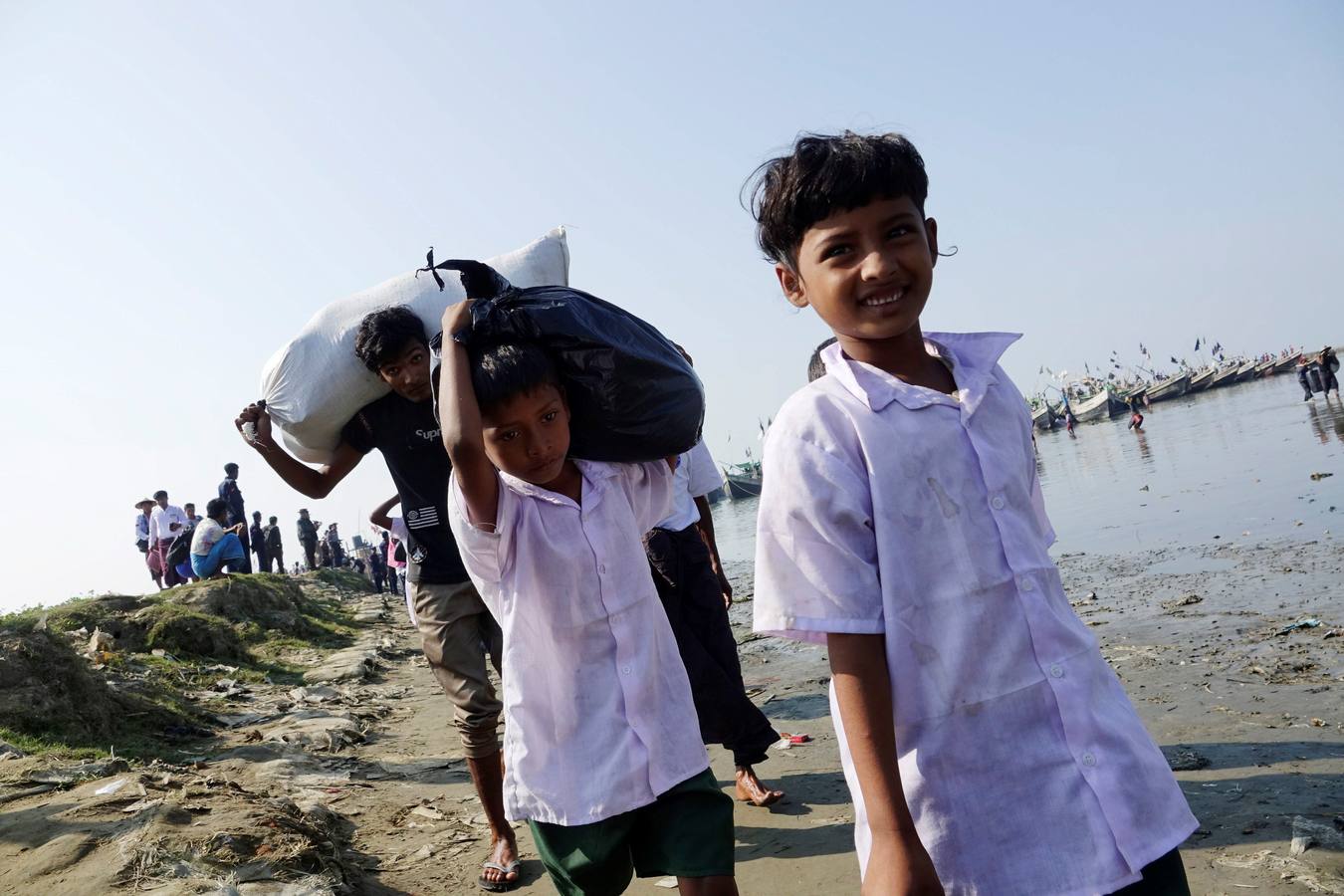 Policías birmanos escoltan al grupo de 106 rohinyás de vuelta a Sittwe en el estado de Rakáin (Birmania). El pasado 16 de noviembre, el barco en el que viajaban los 106 rohinyás encalló en la costa cerca de Rangún, con uno de sus ocupantes muerto, cuando trataba de llegar a Malasia. 