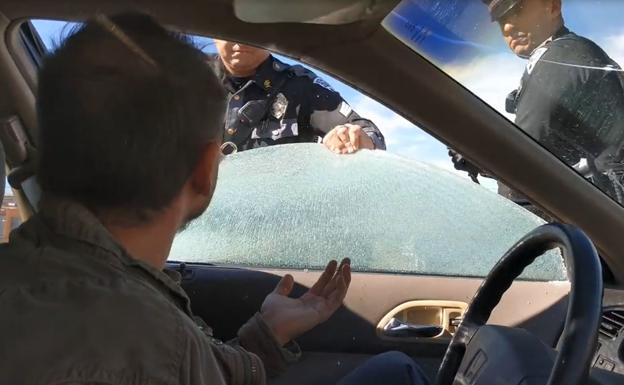 Un policía rompe la ventanilla de un coche 