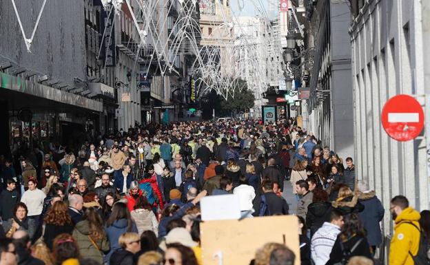 Numerosas personas caminan por una calle comercial de Madrid. 