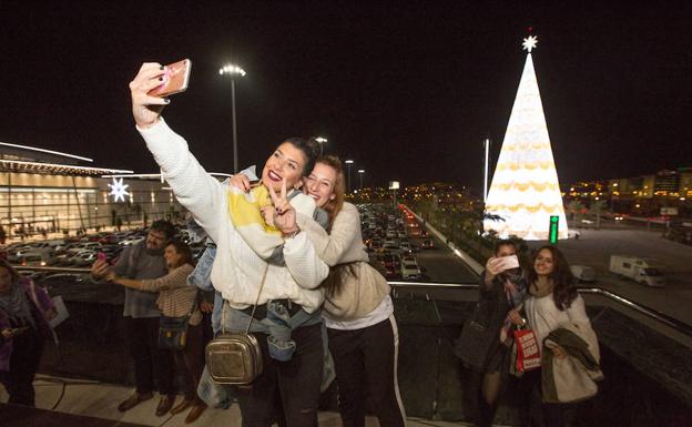 Dos chicas se hacen un selfie con el árbol de Navidad más grande de Europa, en Granada.