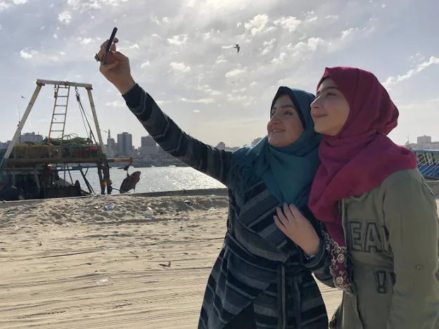 Kholoud Nassar, con el pañuelo rojo, se hace un selfi con una amiga en la bahía de Gaza, y algunas de sus fotos de la cuenta de Instagram. :: m. ayestaran