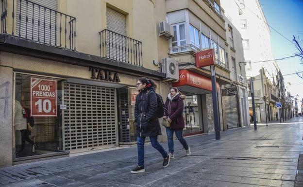 Dos pacenses pasan por la calle Menacho el primer domingo de este mes, con tiendas cerradas.