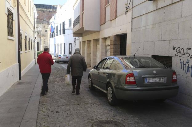 Dos hombres se tienen que bajar de la acera, ocupada por un coche. :: j. m. romero