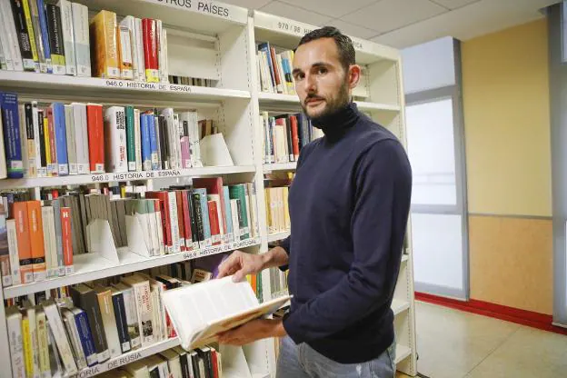 David Conde consultando un libro de la biblioteca de Cáceres. 