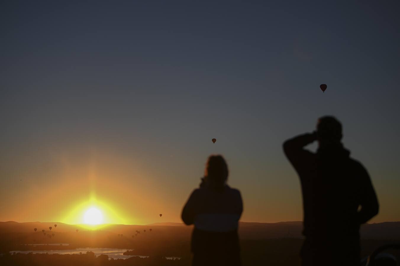 Observan cómo los globos aerostáticos se elevan sobre el lago Burley-Griffin durante el festival internacional de globos de Camberra, Australia. El festival es considerado como uno de los más grandes del mundo.