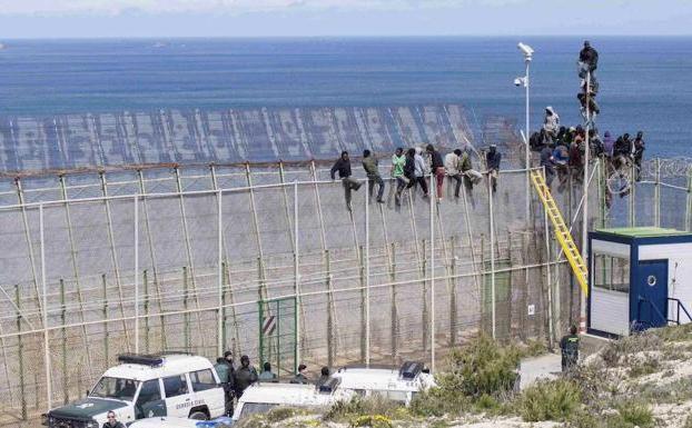 Imagen de archivo del vallado de Ceuta, con varios inmigrantes encaramados al mismo. 