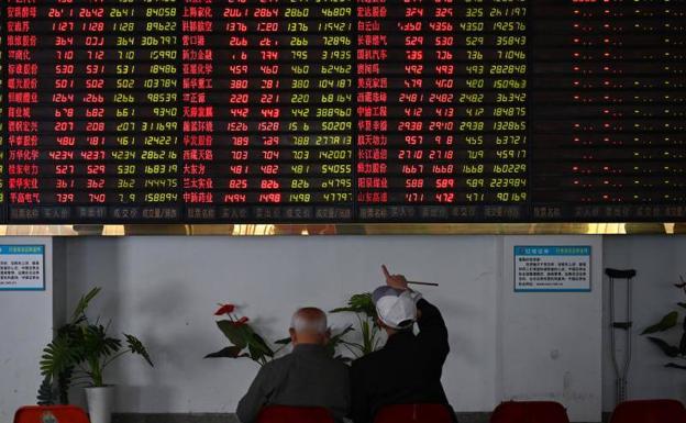 Dos inversores observan un panel informativo en la bolsa de Shanghai.