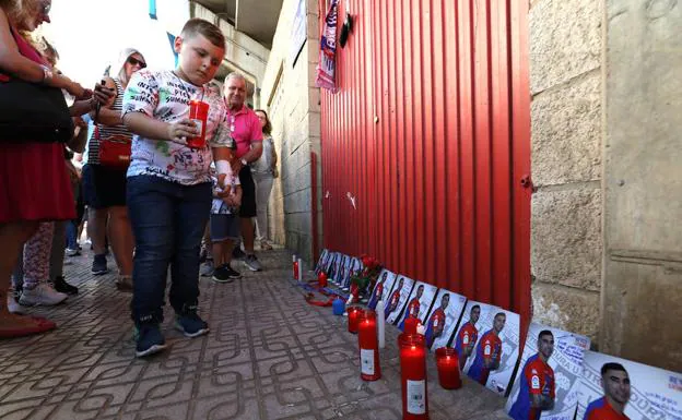 Un niño deposita una vela delante de las fotos del jugador en la puerta 19 del estadio almendralejense.: BRÍGIDO