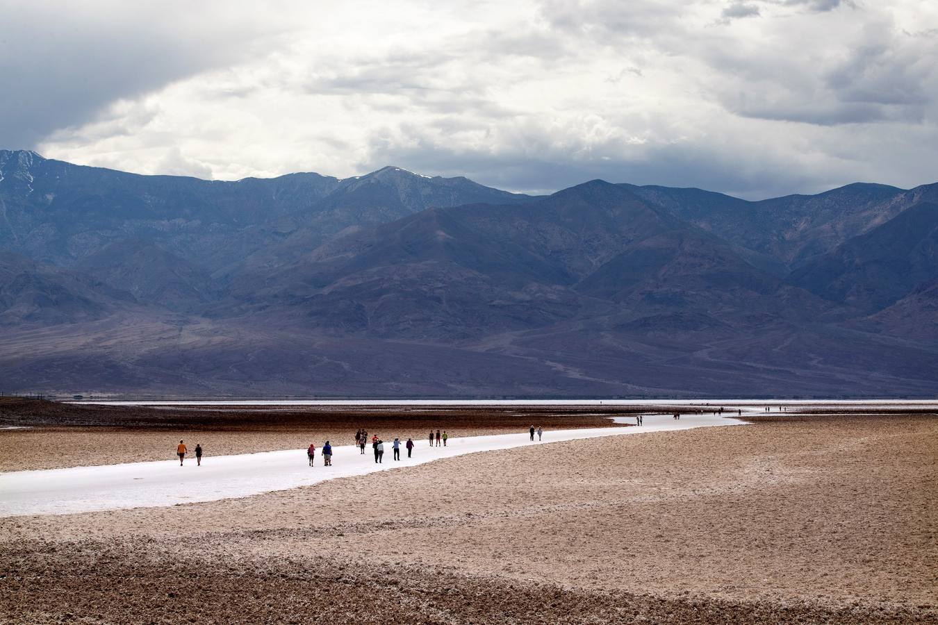 Varios turistas caminan por una salina seca de la cuenca ''Badwater'', situada a 855 metros por debajo del nivel del mar, en el Valle de la Muerte, cercano a Furnace Creek