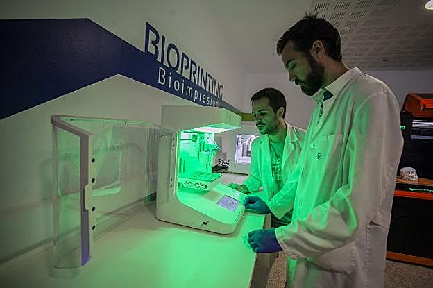 Los investigadores Juan Carlos Gómez y Enrique Mancha observando el trabajo que realiza una de las bioimpresoras 3D del laboratorio. 