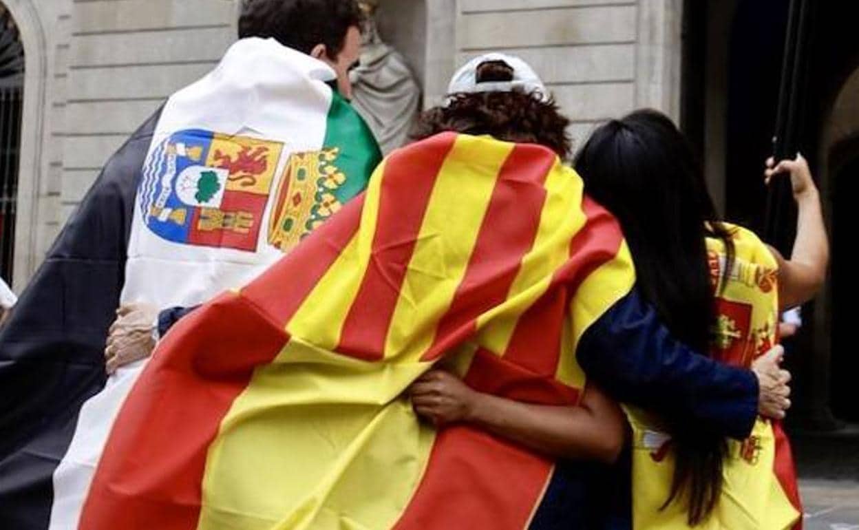 Imagen de archivo de tres personas con las banderas de Extemadura, Cataluña y España en la puerta del Ayuntamiento de Barcelona. 