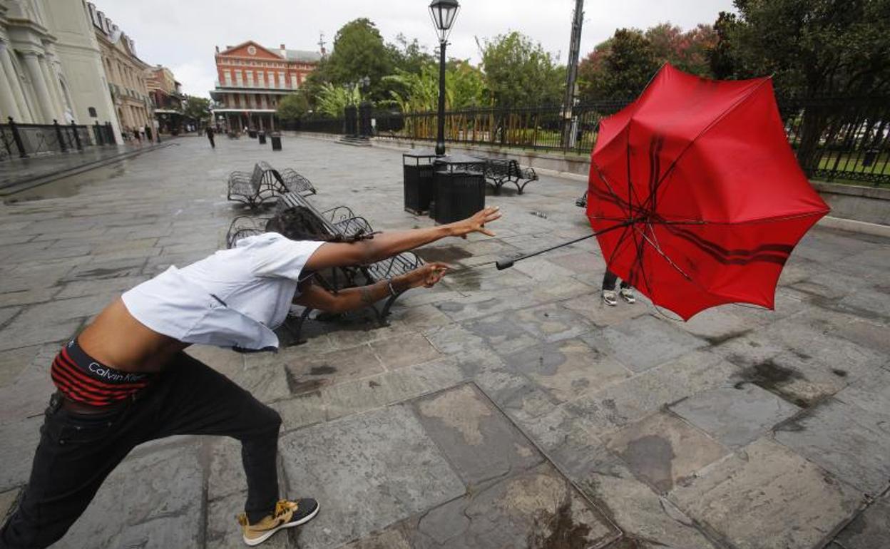 Un hombre sufre el vuelo de su paraguas a consecuencia del fuerte viento en Lousiana. 