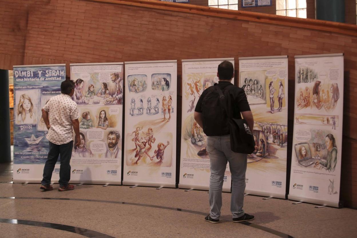 Dos personas observan los paneles de la muestra. :: j. m. romero