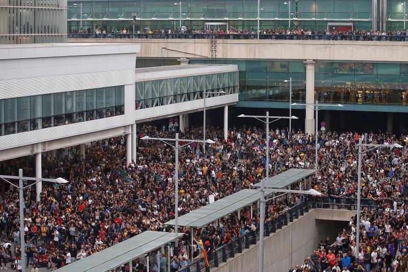 Miembros de los Mossos d'Esquadra cargan contra los centenares de personas que se agolpan ante el Aeropuerto del Prat 