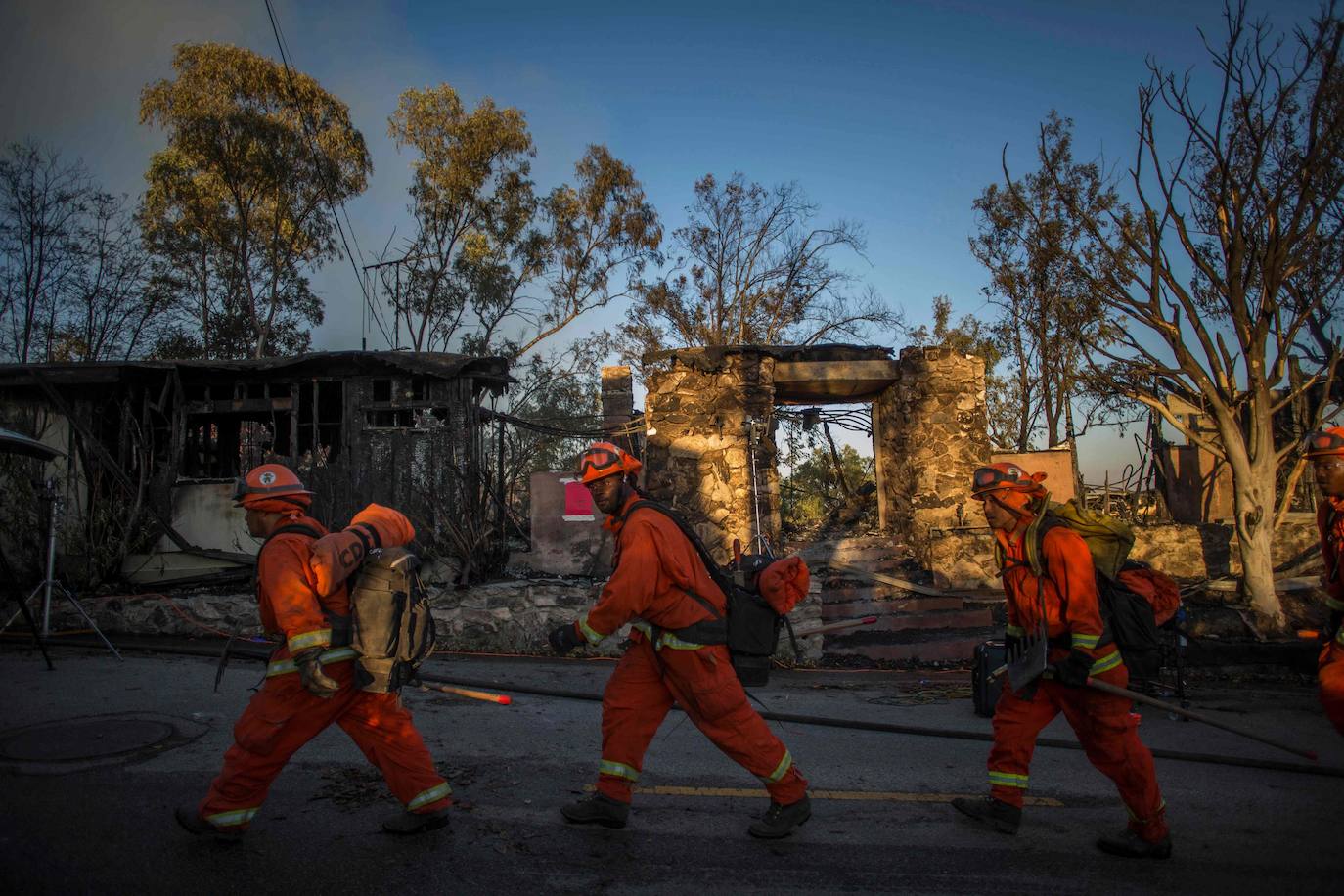 Bomberos pasan frente a una casa calcinada durante el 'Getty Fire'