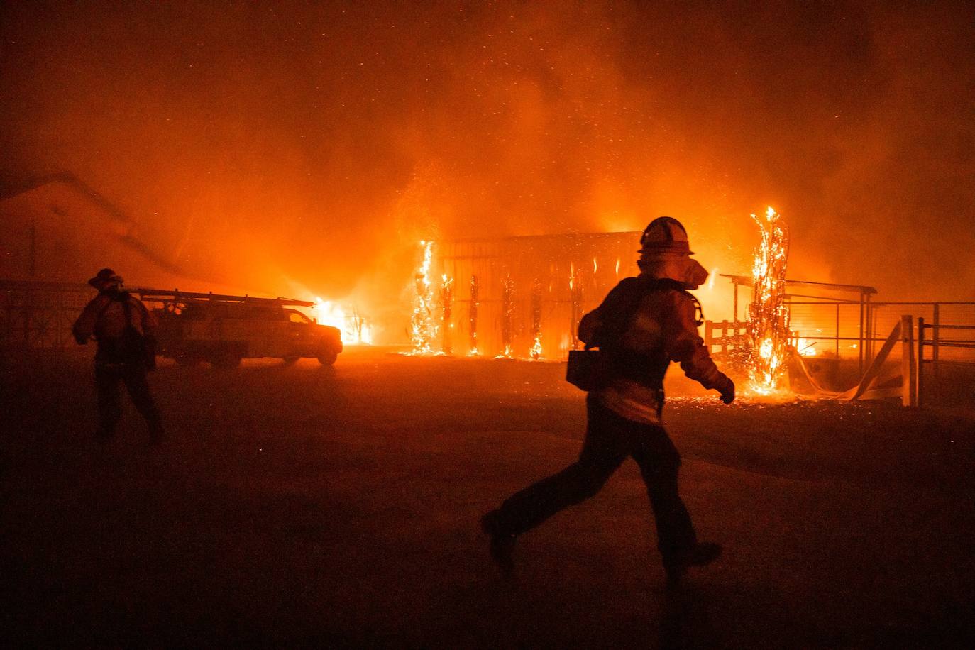 Bomberos frente a una granja en llamas durante el incendio Kincade
